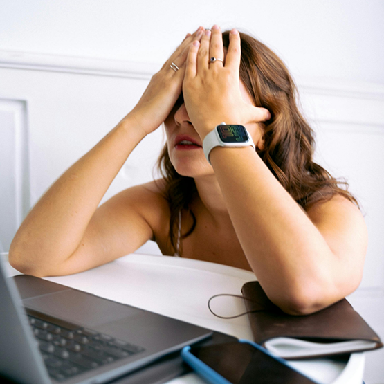 Woman at her work desk laying her face in her hands