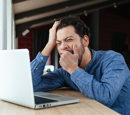 Man sitting at his work desk and yawning