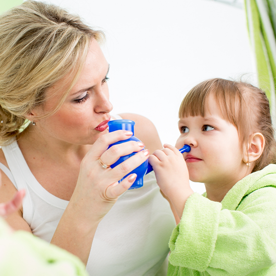 Mother helping her child use a nasal irrigation pot