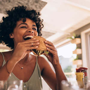 Chicago patient smiling with dental implants as they eat a burger