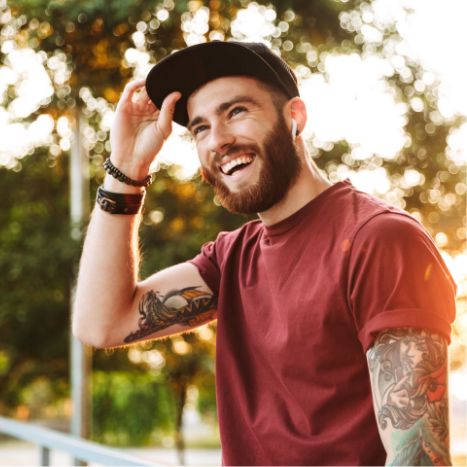 Young man with tattoo sleeves smiling in the sun