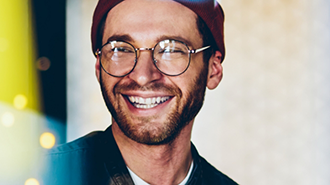 Young man in glasses and a beanie smiling after dental services in Chicago