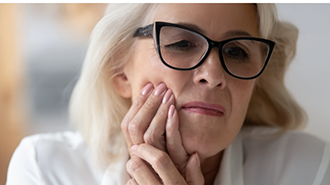 Older woman holding the side of her face in pain