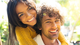 Young man and woman smiling and embracing outdoors