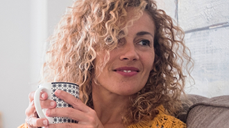 Woman with curly hair holding a cup of coffee