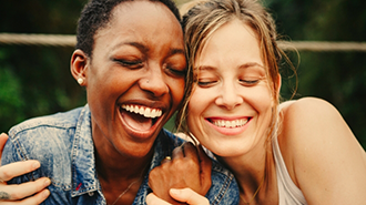 Two women laughing and hugging