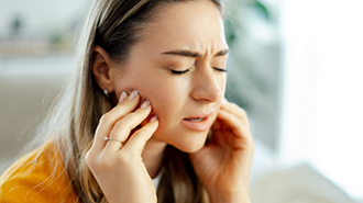 Woman holding both sides of her jaw in pain