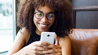 Young woman smiling while looking at her phone